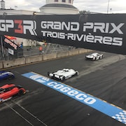 Une banderole du Grand Prix de Trois-Rivières et des voitures qui passent en dessous.