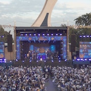 Une scène et plusieurs spectateurs brandissent des drapeaux du Québec.
