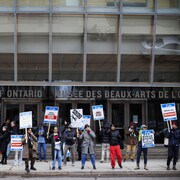 Des employés sur le piquet de grève avec des pancartes devant le musée.