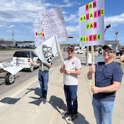 Des manifestants tiennent des pancartes le long d'un boulevard à Baie-Comeau.