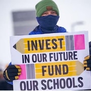 Une personne tient une pancarte tout en marchant à une manifestation lors d'une journée de grève organisée par les membres de la Fédération des enseignants de la Saskatchewan à Saskatoon en janvier.