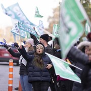 Des grévistes brandissent des drapeaux en bordure d'une rue.