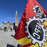 Un drapeau de l'Alliance de la Fonction publique du Canada qui flotte devant le parlement.