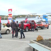 Des employés munis de travaux au logo d'Unifor et, à droite, une affiche en verre annonçant l'usine de Prelco.