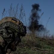 Un soldat avec en arrière-plan un nuage de fumée noire. 