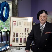 un vétéran de la seconde guerre mondiale à côté d'un cadre de médailles