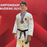 Guillaume Gaulin, le champion canadien en judo debout avec sa médaille au cou.