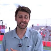 Un homme regarde la cam&eacute;ra dans un stade de tennis.