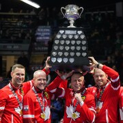 Les joueurs de l'équipe Canada, vêtus de leur uniforme rouge, soulèvent le trophée du Brier.