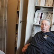 Un homme devant des cartables de journaux.