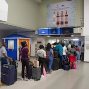 Des voyageurs font la file dans un hall d'aéroport.