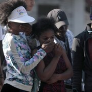 Des Haïtiens regardent avec effroi les corps calcinés de membres de gangs dans une rue de la capitale Port-au-Prince.