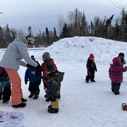 Les enfants jouent dans la neige avec deux éducatrices.