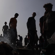 Des Palestiniens autour d'objets encore fumant à la suite d'une attaque israélienne. 