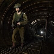 Un militaire marche dans un tunnel sombre et large.