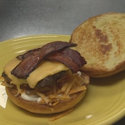 Un burger au fromage avec bacon et croustilles.