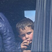 Un garçon mange en regardant par la fenêtre de son autobus.