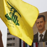 Un drapeau du Hezbollah flottant devant un portrait du président syrien Bachar Al-Assad.