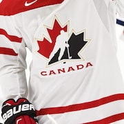 Le logo de Hockey Canada apparaît sur l'uniforme blanc que deux joueurs d'Équipe Canada portent pendant un match au Championnat mondial de hockey junior le 28 décembre 2015 à Helsinki, en Finlande.