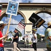 Des manifestants avec des pancartes devant un édifice.