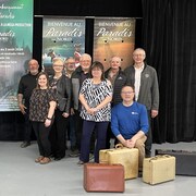 20 chanteurs et comédiens posent près de valises de voyage et des affiches du spectacle hommage au Paradis du Nord.