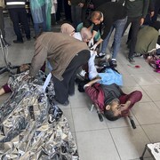 Des gens aident une personne blessée au sol dans un hôpital.