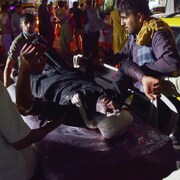 Un homme visiblement blessé transporté sur une civière. 