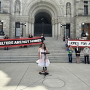 Des personnes avec des banderoles pour le droit au logement, devant l'Assemblée législative, à Victoria, le 7 mai 2024.