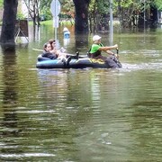 Des sinistrés naviguent dans les rues de Houston à bord d'une petite embarcation gonflable.