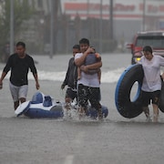 Un groupe de sinistrés marchent dans une rue inondée.