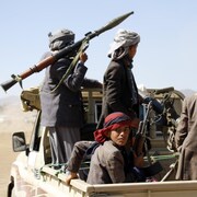 Des combattants arm&eacute;s dans le coffre arri&egrave;re d'une camionnette.