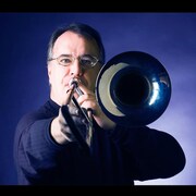 Hugh Fraser, dans une photo, tient un trombone.