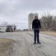 Miguel Lord pose devant un tracteur et les silos d'une ferme.
