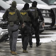 Trois agents de l'ICE marchent dans un stationnement.