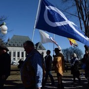 Des personnes tenant des drapeaux métis dans la main.