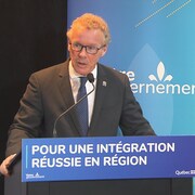 Le ministre de l'Immigration, de la Francisation et de l'Intégration, Jean Boulet, fait une allocution au micro dans une salle de conférence. 