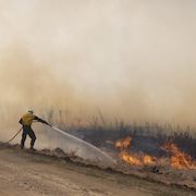Des pompiers tentent de maîtriser un feu de broussailles près de Biggar, en Saskatchewan.