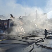 Un pompier en train d'arroser un bâtiment en ruines.