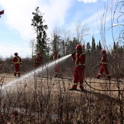 Des personnes en tenue de pompiers éteignent un feu. 