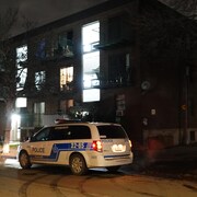 Une camionnette de police stationnée la nuit près d'un édifice.