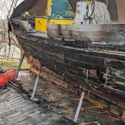 Gros plan sur la coque en bois brûlée du bateau. 
