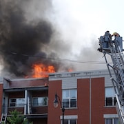 Des pompiers dans une nacelle tentent de maîtriser un incendie.