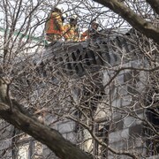Des pompiers sur le toit d'un édifice incendié.