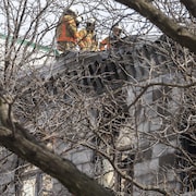 Des pompiers sur le toit d'un édifice incendié.