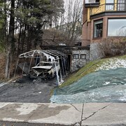 Une voiture incendie sous une structure de métal parsemée de plastique déchiqueté.