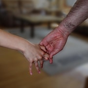 Une main d'homme prend la main d'une petite fille dans une résidence.