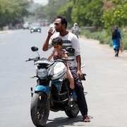 Un homme et un enfant boivent des boissons rafraîchissantes proposées par les habitants lors d'une chaude journée d'été pendant une canicule à Narela, New Delhi, Inde, le 29 mai 2024.