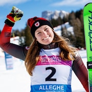 Une skieuse sourit et lève le poing droit en signe de victoire.