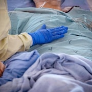 La main gantée d'un professionnel de la santé sur la poitrine d'un patient à l'hôpital.
