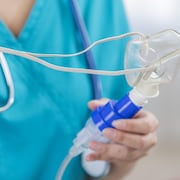 Une inhalothérapeute tient un masque.
